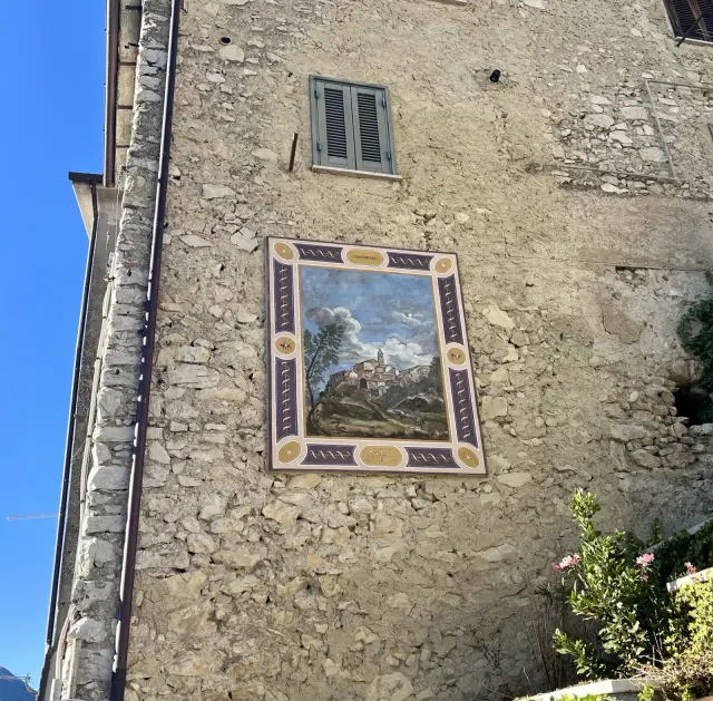 Affresco decorativo raffigurante il borgo dipinto sulla facciata di un edificio in pietra