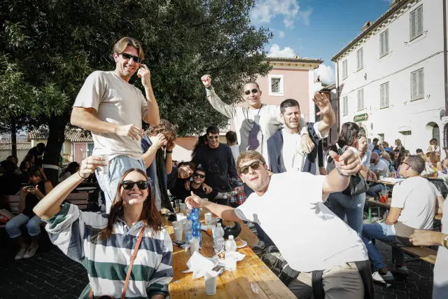 Gruppo di amici in posa scherzosa a un tavolo durante la sagra