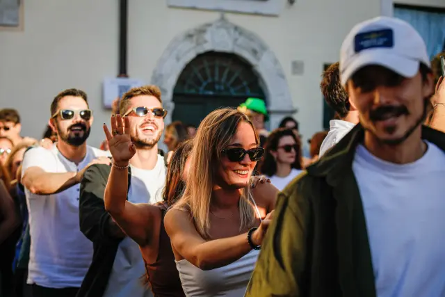Gruppo di visitatori sorridenti che camminano e salutano tra la folla