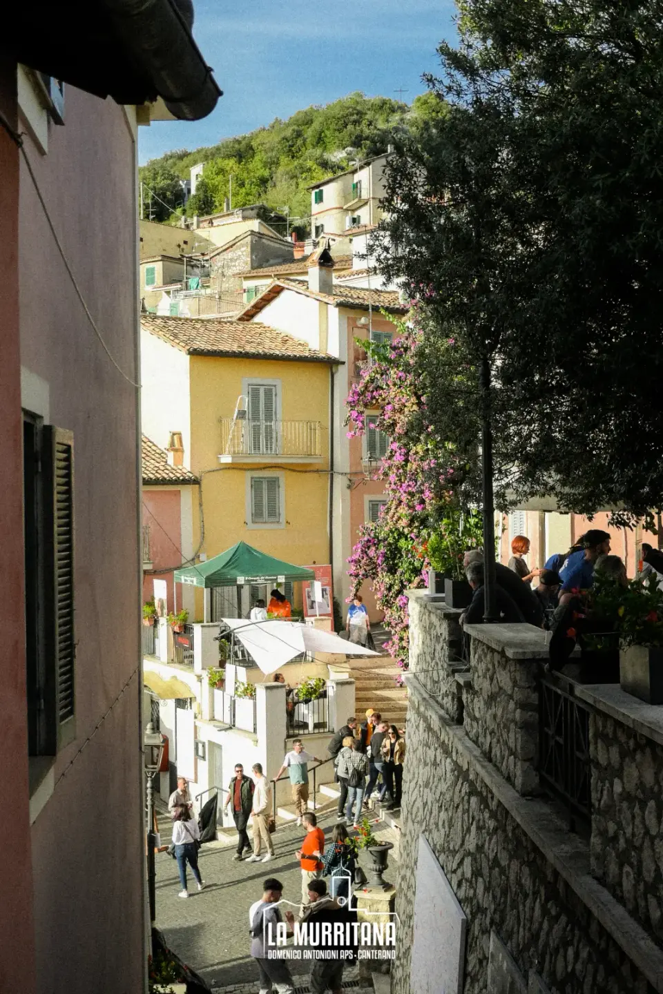 Vicolo caratteristico di Canterano con case colorate, bouganville fiorita e visitatori